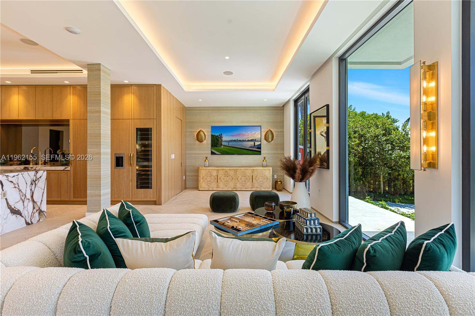 A modern living room features a white sectional sofa, wood cabinetry, and floor-to-ceiling windows — 2499 N Meridian Ave, Miami Beach FL 33140, MIAMI BEACH, FL