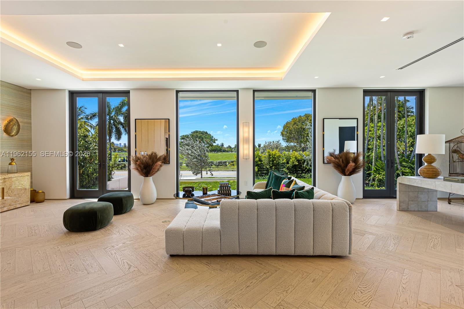 A modern living room features a textured sofa, herringbone wood floors, and large glass doors — 2499 N Meridian Ave, Miami Beach FL 33140, MIAMI BEACH, FL