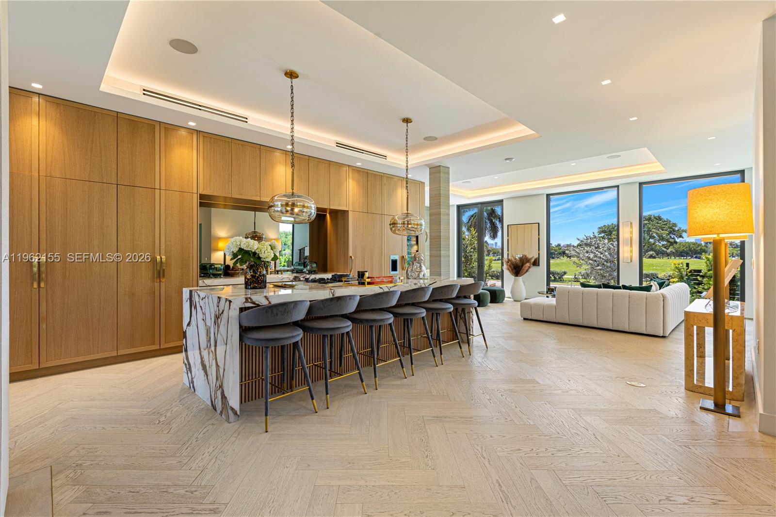 A modern kitchen features wood cabinetry, a marble island with bar seating, and herringbone flooring — 2499 N Meridian Ave, Miami Beach FL 33140, MIAMI BEACH, FL