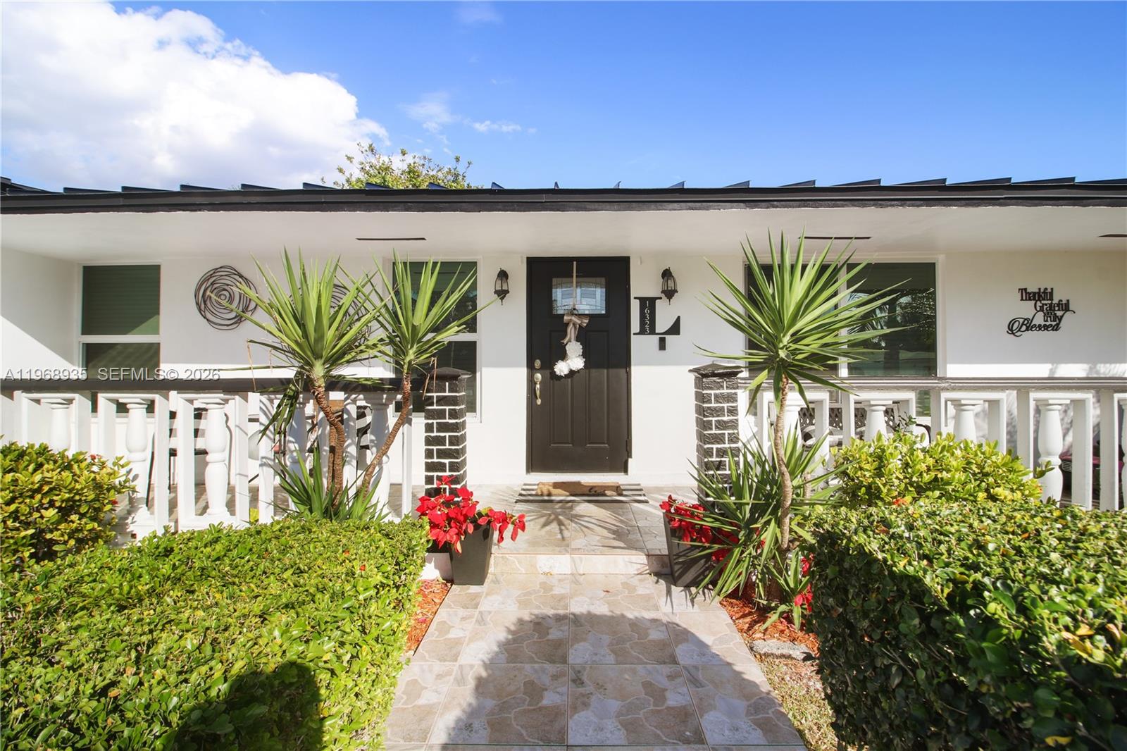 The exterior of a white house features a black front door, porch railings, and landscaping — 16323 SW 103rd Pl, Miami FL 33157, MIAMI, FL
