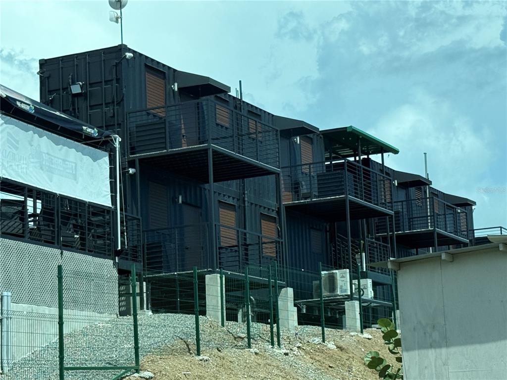 A multi-story building constructed from stacked black shipping containers with metal balconies and exterior staircases — SR 545 km 1.5 SECTOR GABIA HACIENDAS DEL SUR TENNIS CLUB, SANTA ISABEL, PR