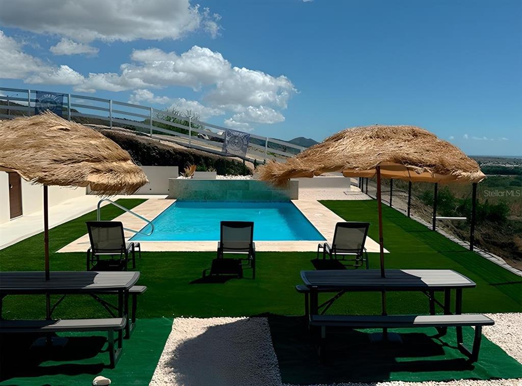 A swimming pool with lounge chairs and picnic tables sits on a grassy patio area — SR 545 km 1.5 SECTOR GABIA HACIENDAS DEL SUR TENNIS CLUB, SANTA ISABEL, PR