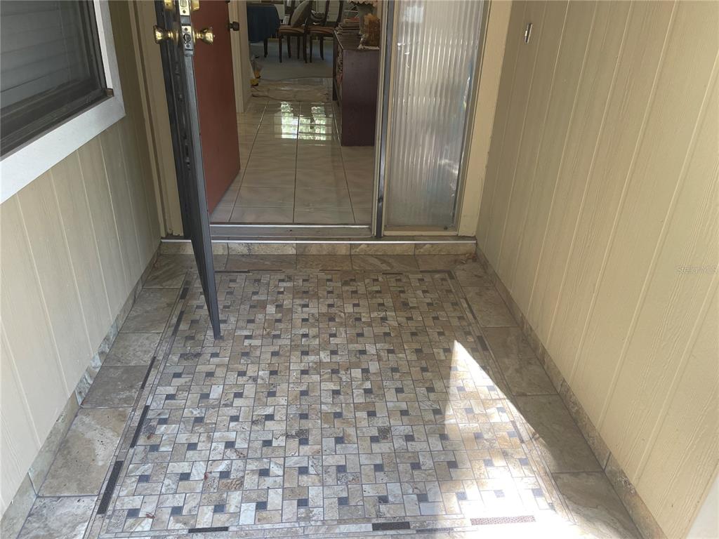 An outdoor entryway features a patterned tile floor leading to an open front door — 4944 VILLAGE GARDENS DRIVE UNIT 151, SARASOTA, FL