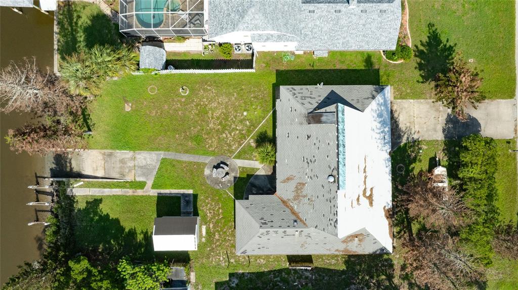 An aerial view shows a house with a gray shingled roof, a backyard, and a dock — 21 CUNNINGHAM DRIVE, NEW SMYRNA BEACH, FL