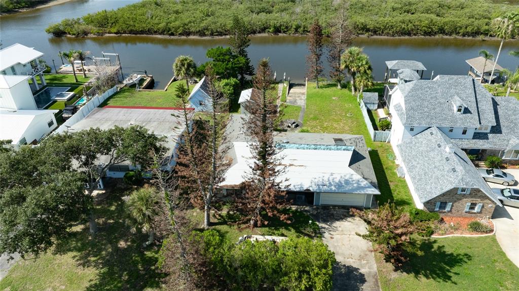 An aerial view shows a house with a white roof, tall trees, and a backyard — 21 CUNNINGHAM DRIVE, NEW SMYRNA BEACH, FL