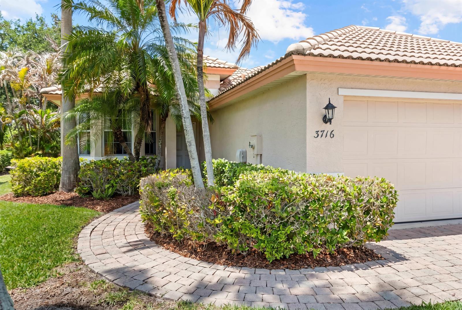 A paved walkway leads to the front entrance of a house with a beige exterior — 3716 NW Deer Oak Drive, Jensen Beach FL 34957, JENSEN BEACH, FL