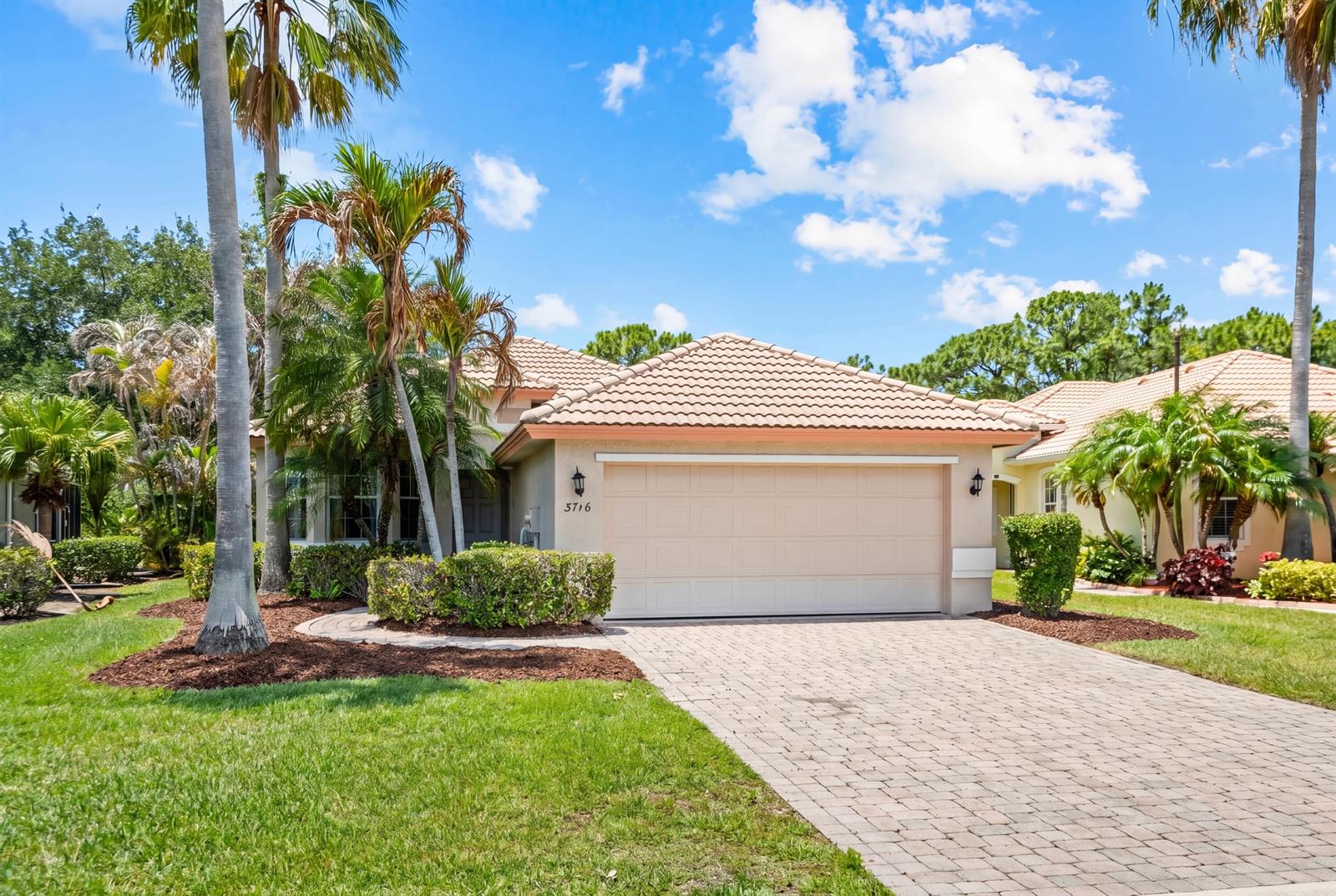 A single-story house with a beige garage, tile roof, and palm trees in the front yard — 3716 NW Deer Oak Drive, Jensen Beach FL 34957, JENSEN BEACH, FL