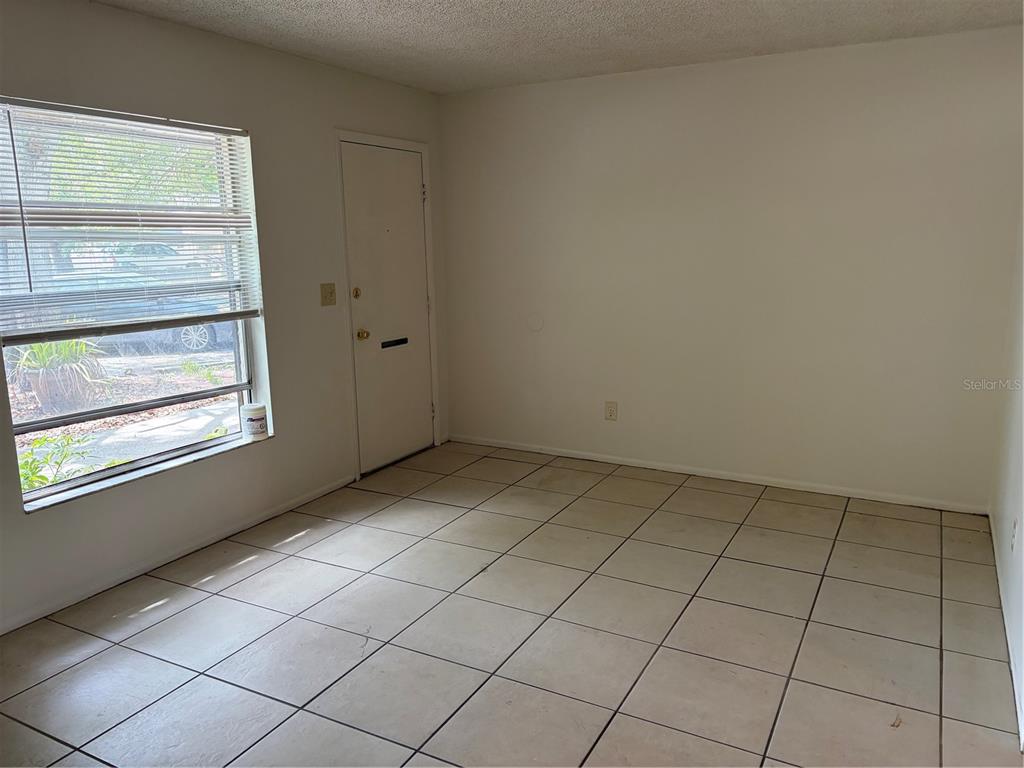 An empty room with beige tile flooring, white walls, and a window with blinds — 176 MARGIE STREET, PALM HARBOR, FL