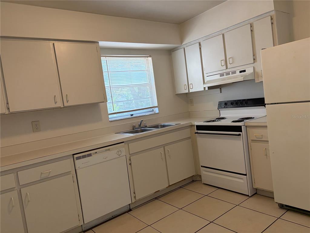 A kitchen features white cabinets, white appliances, a double sink, and light-colored tile flooring — 176 MARGIE STREET, PALM HARBOR, FL