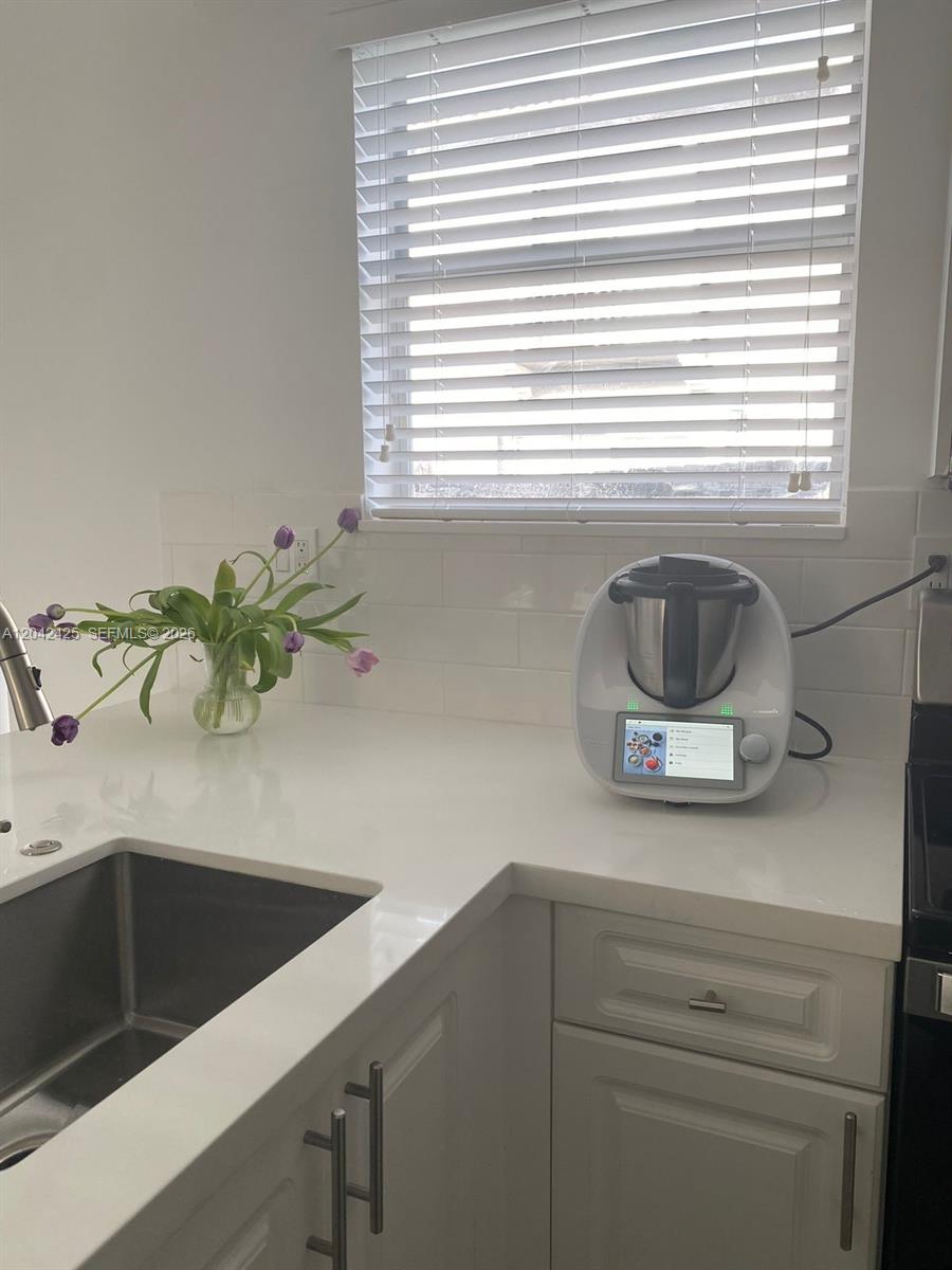 A kitchen counter features a white appliance, a vase of tulips, and a window — 5245 NW 112th Ave # 8, Doral FL 33178, DORAL, FL