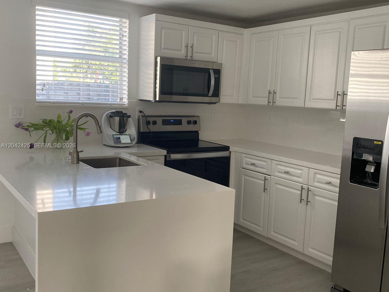 A modern kitchen features white cabinets, stainless steel appliances, and a white quartz countertop island — 5245 NW 112th Ave # 8, Doral FL 33178, DORAL, FL