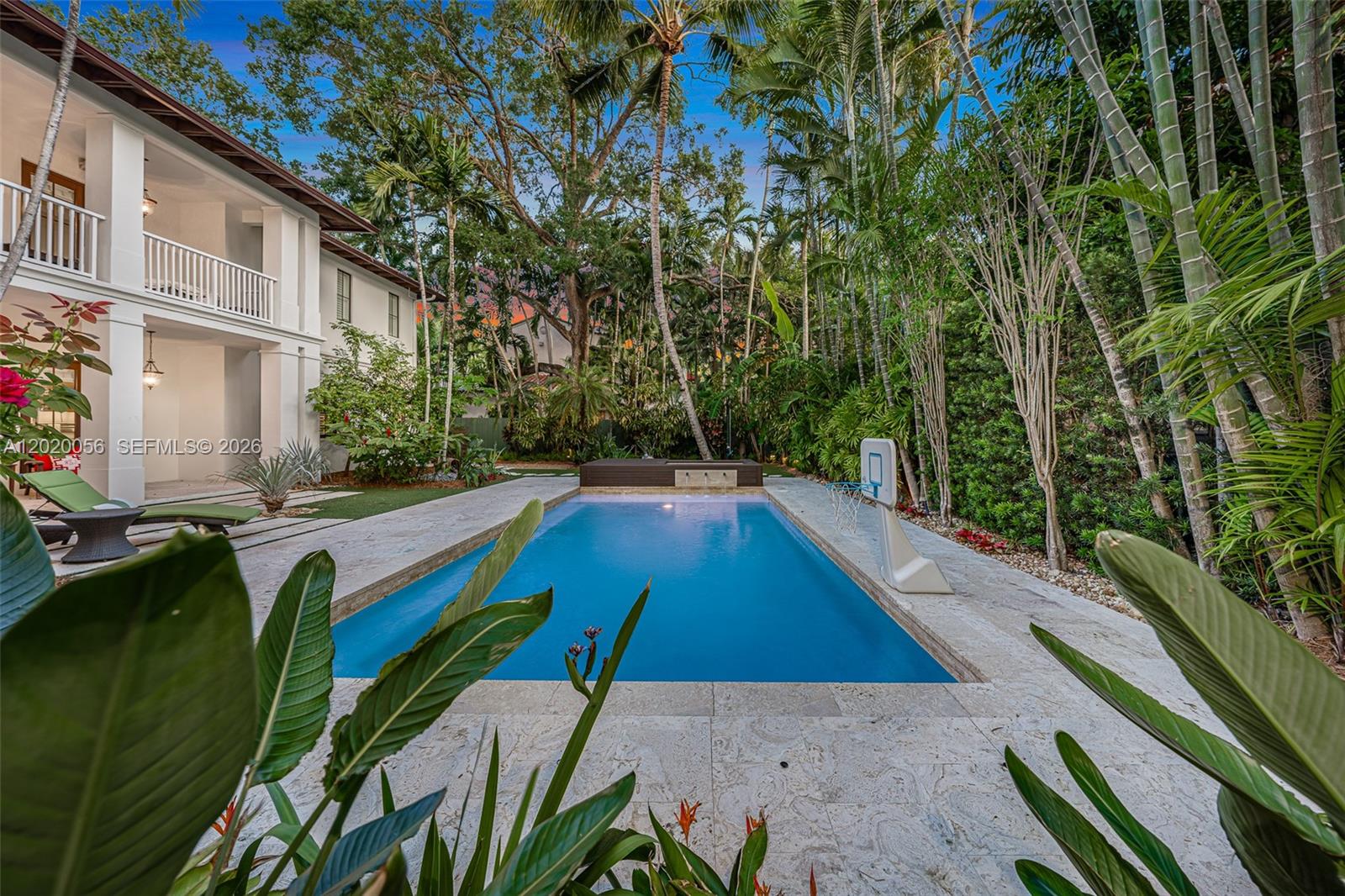 A rectangular swimming pool sits in a backyard patio area next to a two-story house — 4196 S Douglas Rd, Miami FL 33133, MIAMI, FL
