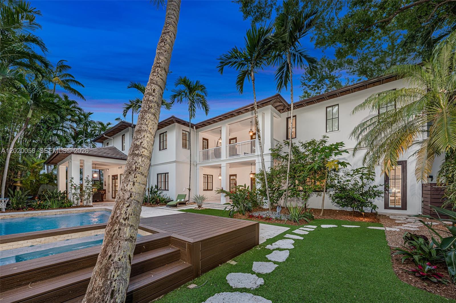 A two-story white house features a swimming pool, wooden deck, and palm trees at dusk — 4196 S Douglas Rd, Miami FL 33133, MIAMI, FL