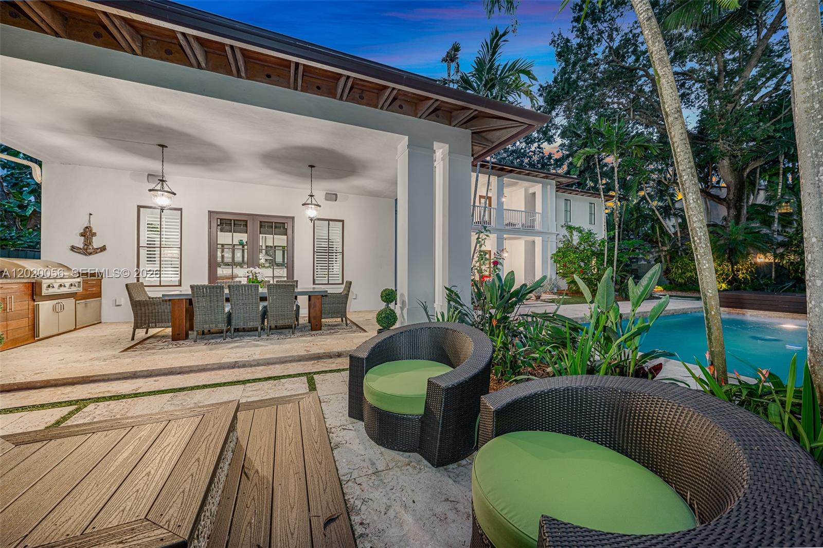 A covered patio features an outdoor kitchen, dining set, and lounge chairs beside a pool — 4196 S Douglas Rd, Miami FL 33133, MIAMI, FL