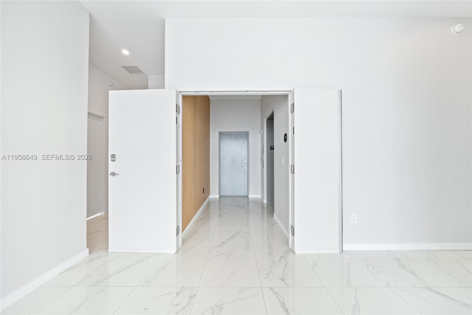 A bright room with white walls and marble-patterned tile flooring features an open doorway — 480 NE 31st St, Miami FL 33137, MIAMI, FL