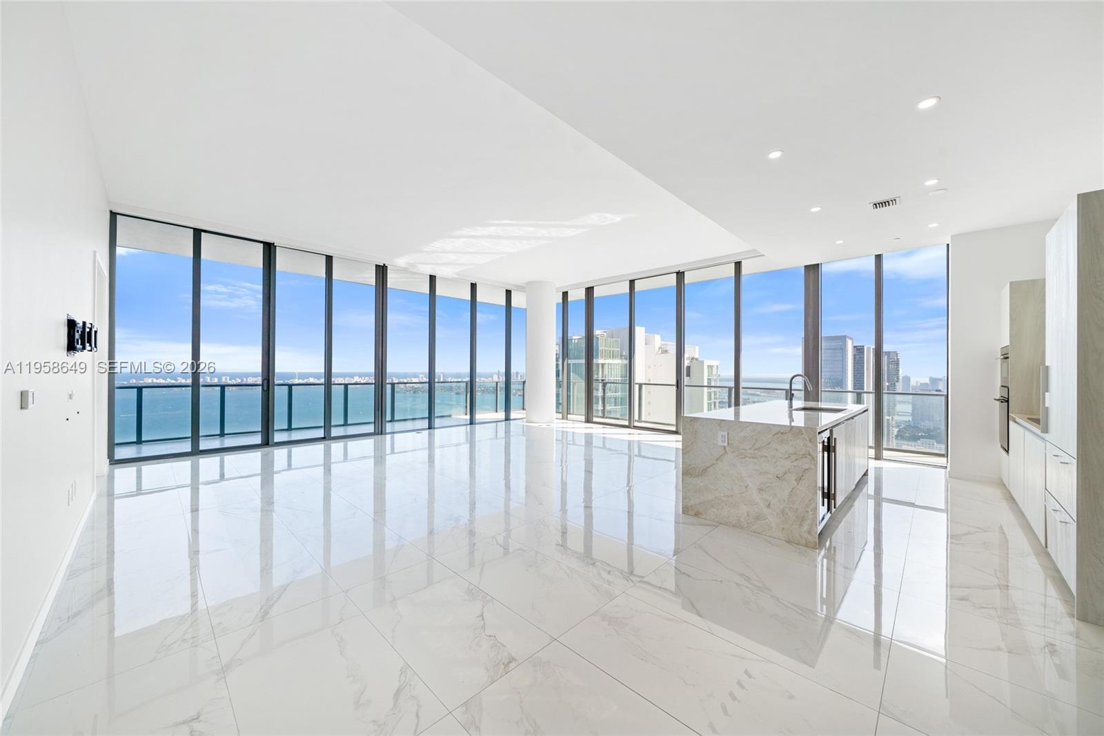 A modern, open-concept kitchen and living area features white marble floors and floor-to-ceiling windows — 480 NE 31st St, Miami FL 33137, MIAMI, FL