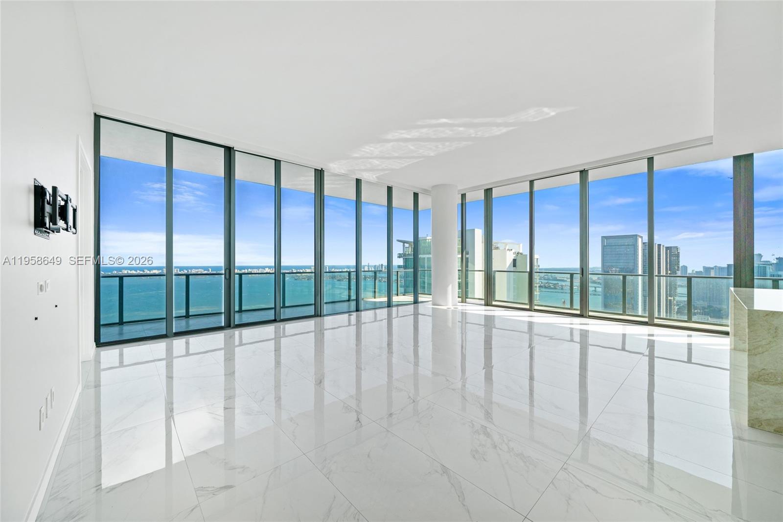 An empty room with white marble floors and floor-to-ceiling windows overlooking the ocean — 480 NE 31st St, Miami FL 33137, MIAMI, FL