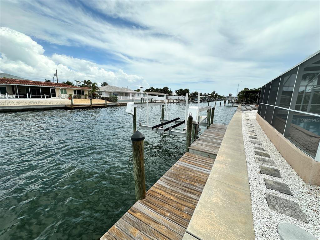 A wooden dock with a boat lift extends into a canal beside a house — 3615 100TH STREET W, BRADENTON, FL
