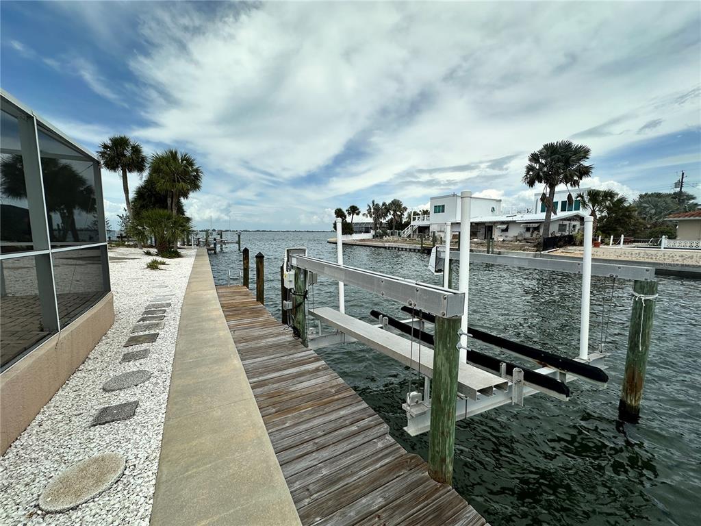 A wooden dock with a boat lift extends into a canal beside a waterfront home — 3615 100TH STREET W, BRADENTON, FL