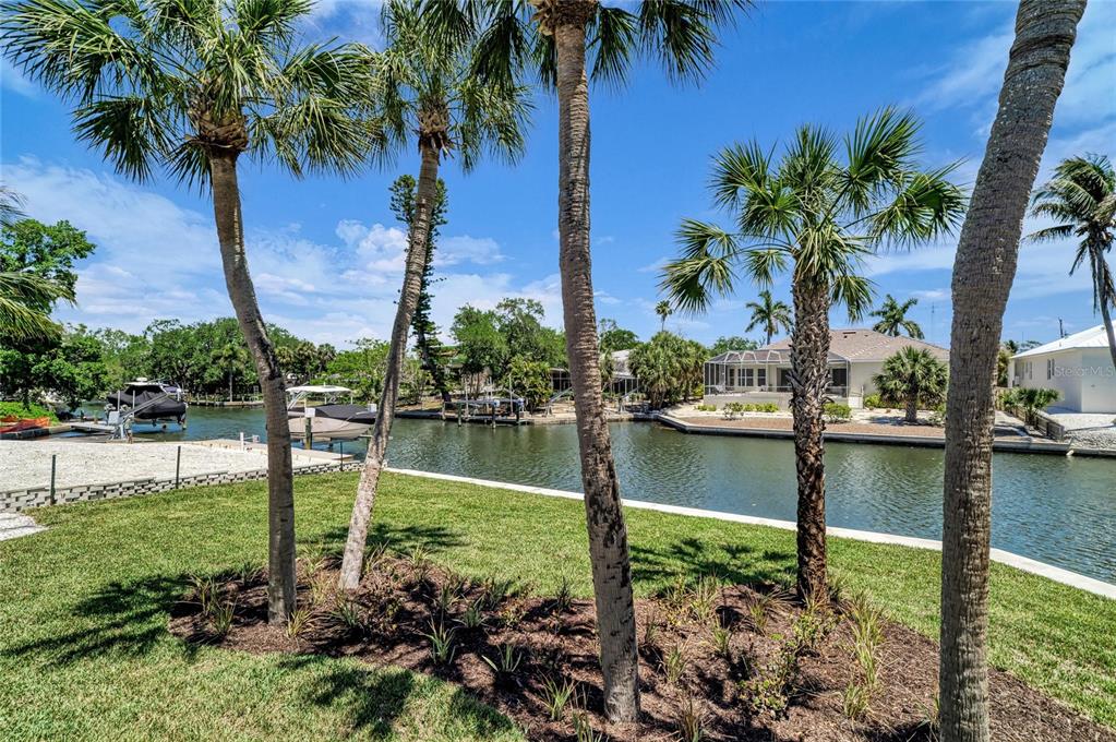 A view of a canal with boats, palm trees, and houses under a blue sky — 5103 WINDWARD AVENUE, SARASOTA, FL