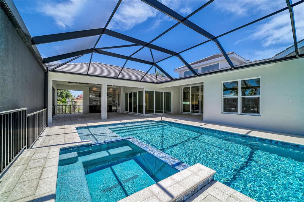 A screened-in patio features a swimming pool, a built-in spa, and a covered outdoor kitchen — 5103 WINDWARD AVENUE, SARASOTA, FL