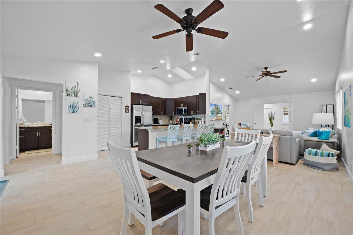 An open-concept living area features a dining table, kitchen island, and light wood-look flooring — 6075 Francis Street, Jupiter FL 33458, JUPITER, FL