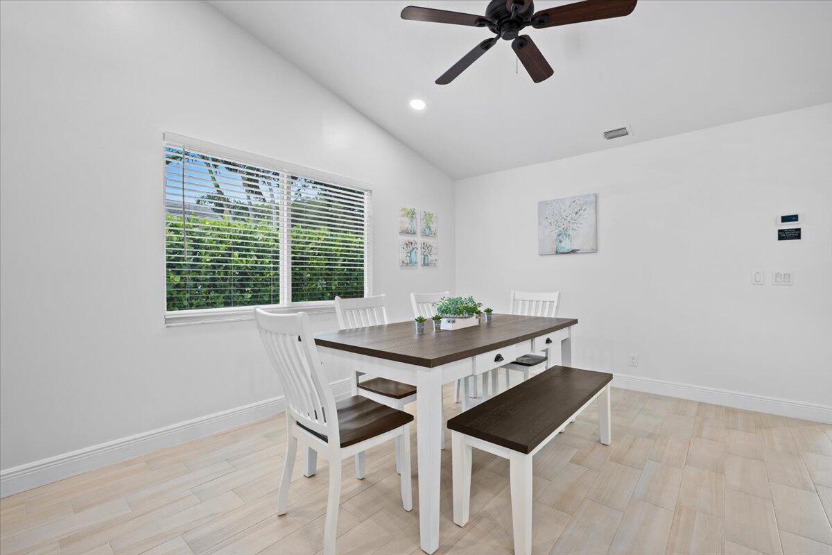 A dining room features a wooden table with a bench, white chairs, and tile flooring — 6075 Francis Street, Jupiter FL 33458, JUPITER, FL