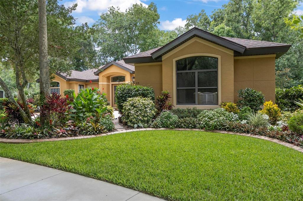 A tan single-story house with a large arched window and lush landscaping in the front yard — 23 CREEKSIDE DRIVE, PALM COAST, FL