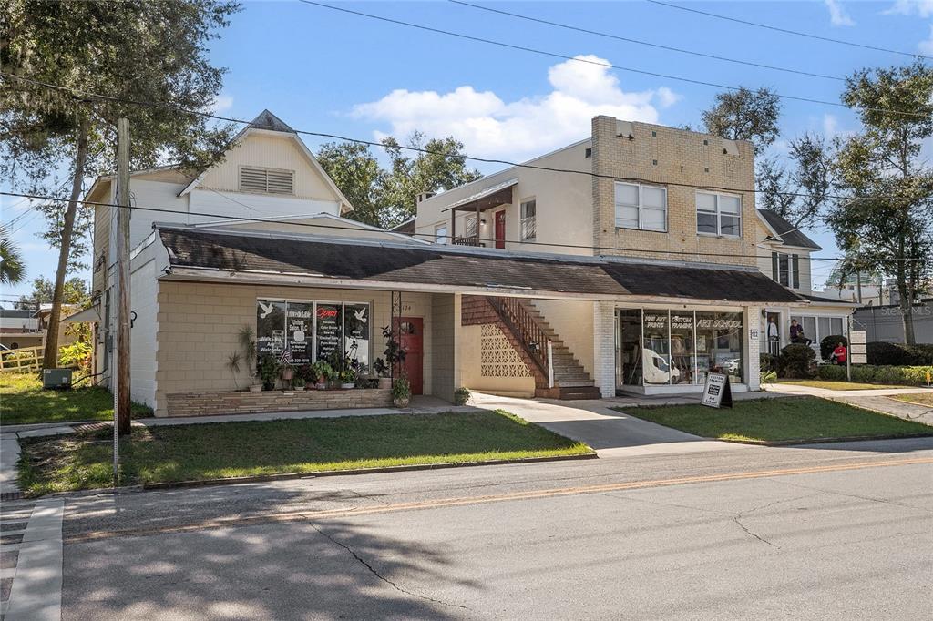 A two-story commercial building with a salon and art school features an exterior staircase — 128 E RICH AVENUE, DELAND, FL