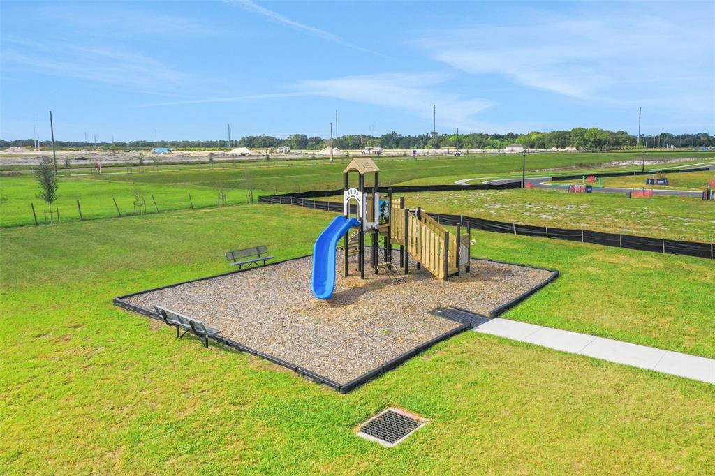 A playground with a blue slide sits on a gravel pad in a grassy field — 4097 PENELOPE AVENUE, LAKE WALES, FL