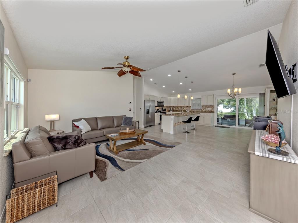 An open-concept living room and kitchen featuring tile floors, a ceiling fan, and neutral walls — 3453 DRYDEN STREET, NORTH PORT, FL