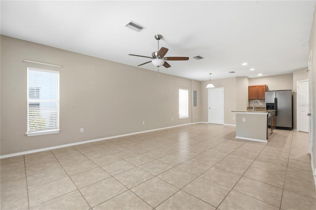 An open-concept living area with tile flooring, a ceiling fan, and an adjacent kitchen — 4715 CHATTERTON WAY, RIVERVIEW, FL