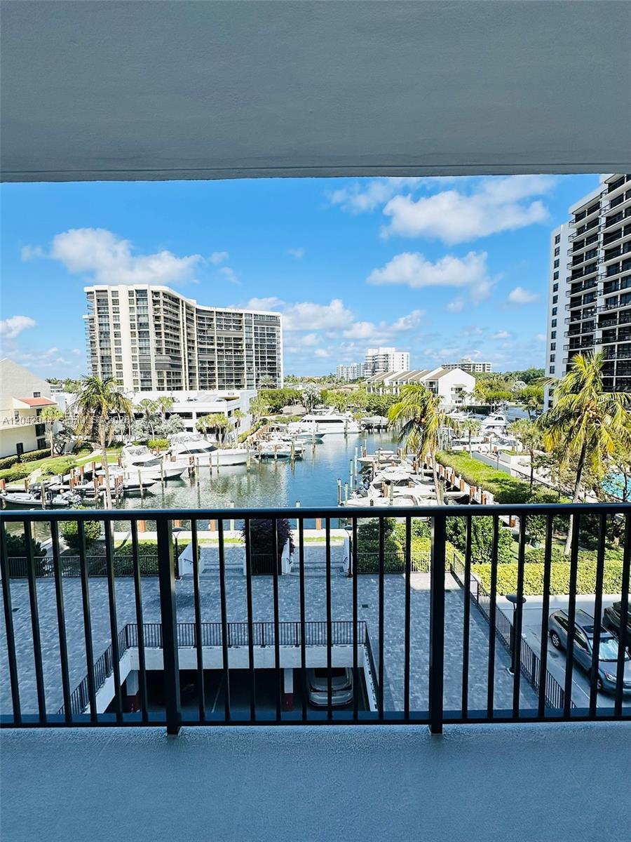 A balcony view overlooks a marina with docked boats and surrounding high-rise apartment buildings — 4750 S Ocean Blvd # 401, Highland Beach FL 33487, HIGHLAND BEACH, FL