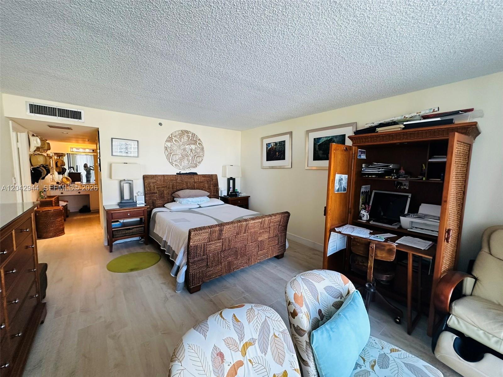 A bedroom features a woven bed frame, a wooden armoire desk, and two patterned chairs — 4750 S Ocean Blvd # 401, Highland Beach FL 33487, HIGHLAND BEACH, FL