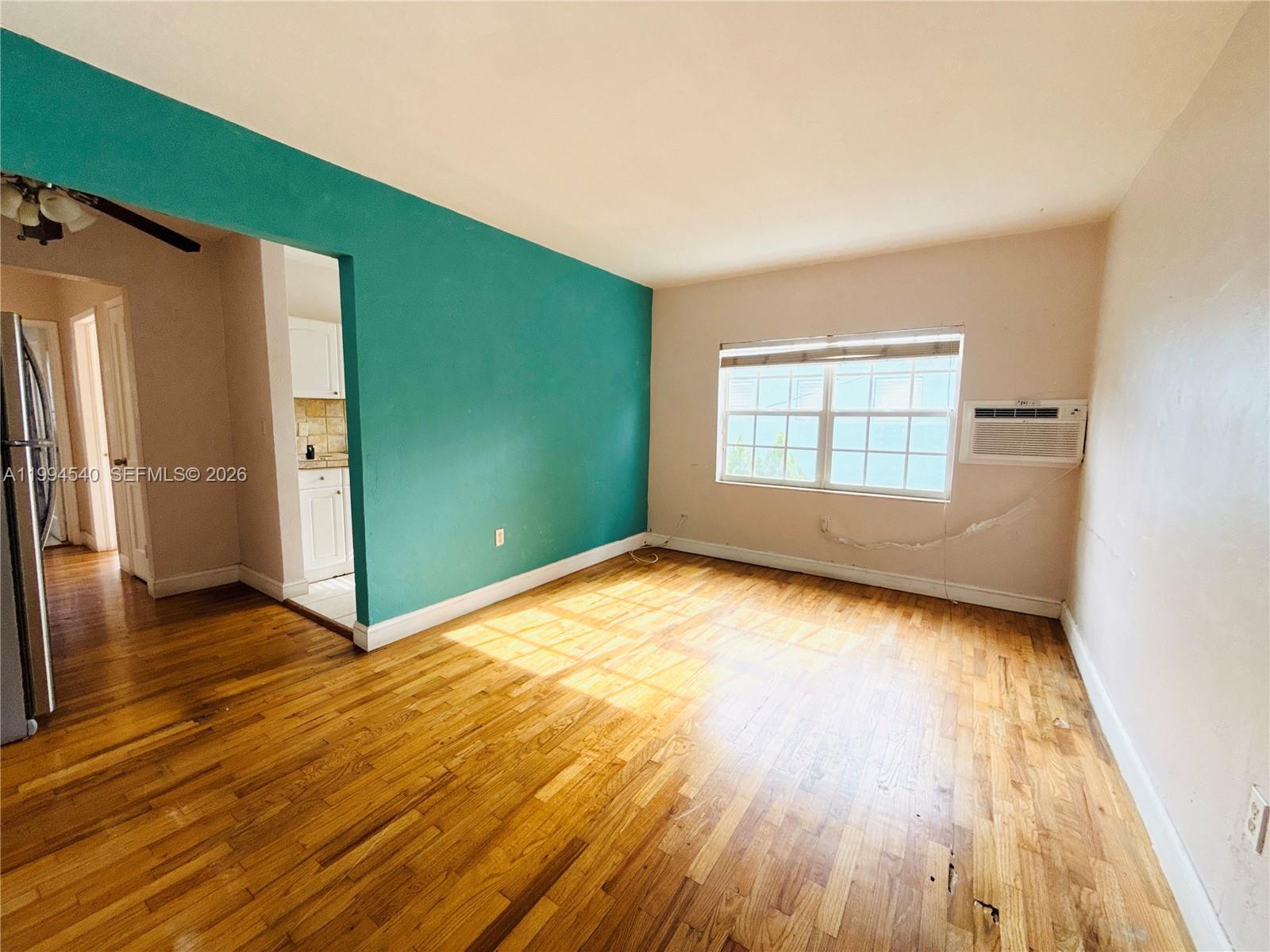 A living room features hardwood floors, a teal accent wall, and a window air conditioner — 555 SW 16th Ave # 11, Miami FL 33135, MIAMI, FL