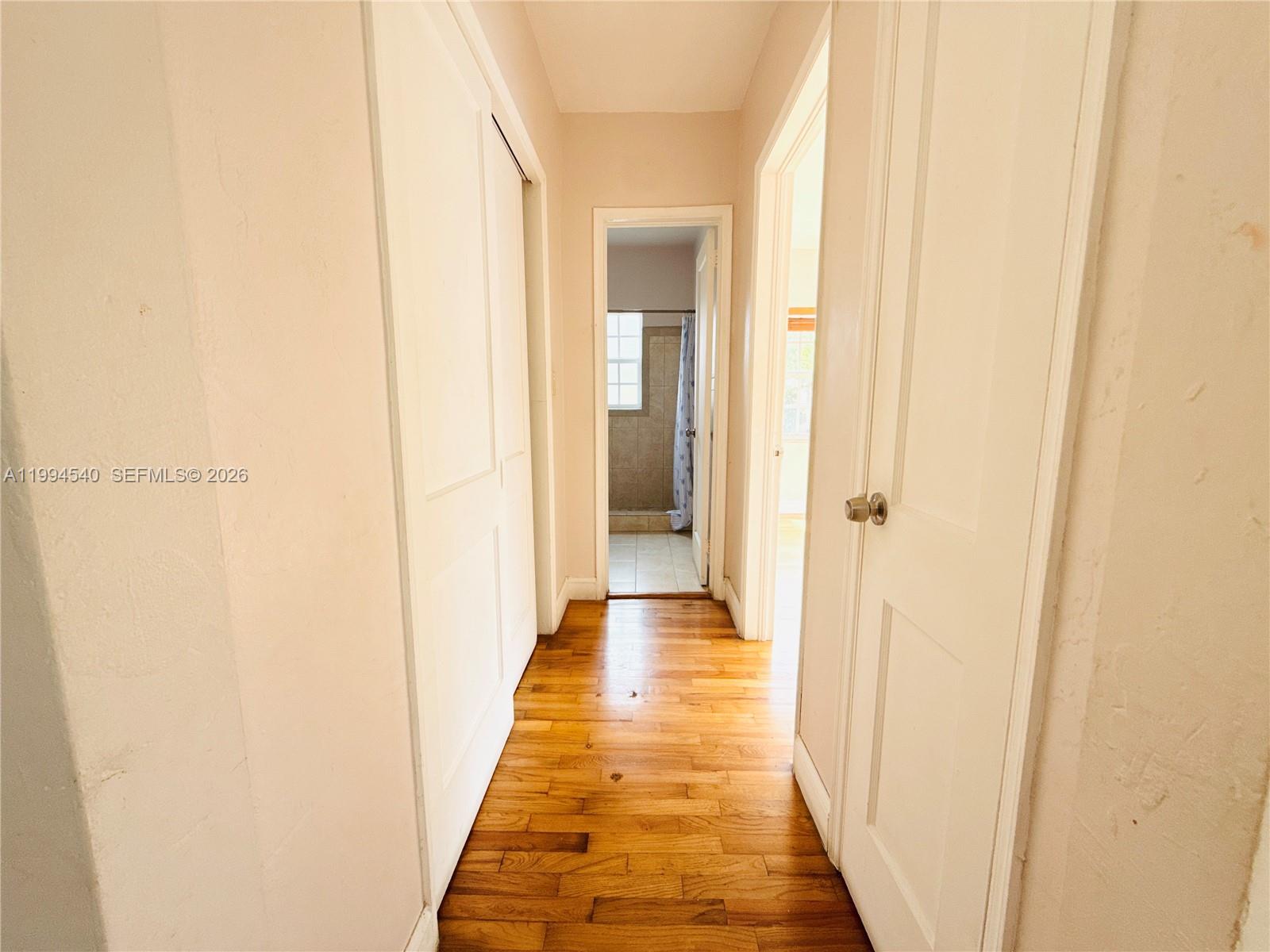 A hallway with hardwood floors leads to a bathroom and another room — 555 SW 16th Ave # 11, Miami FL 33135, MIAMI, FL