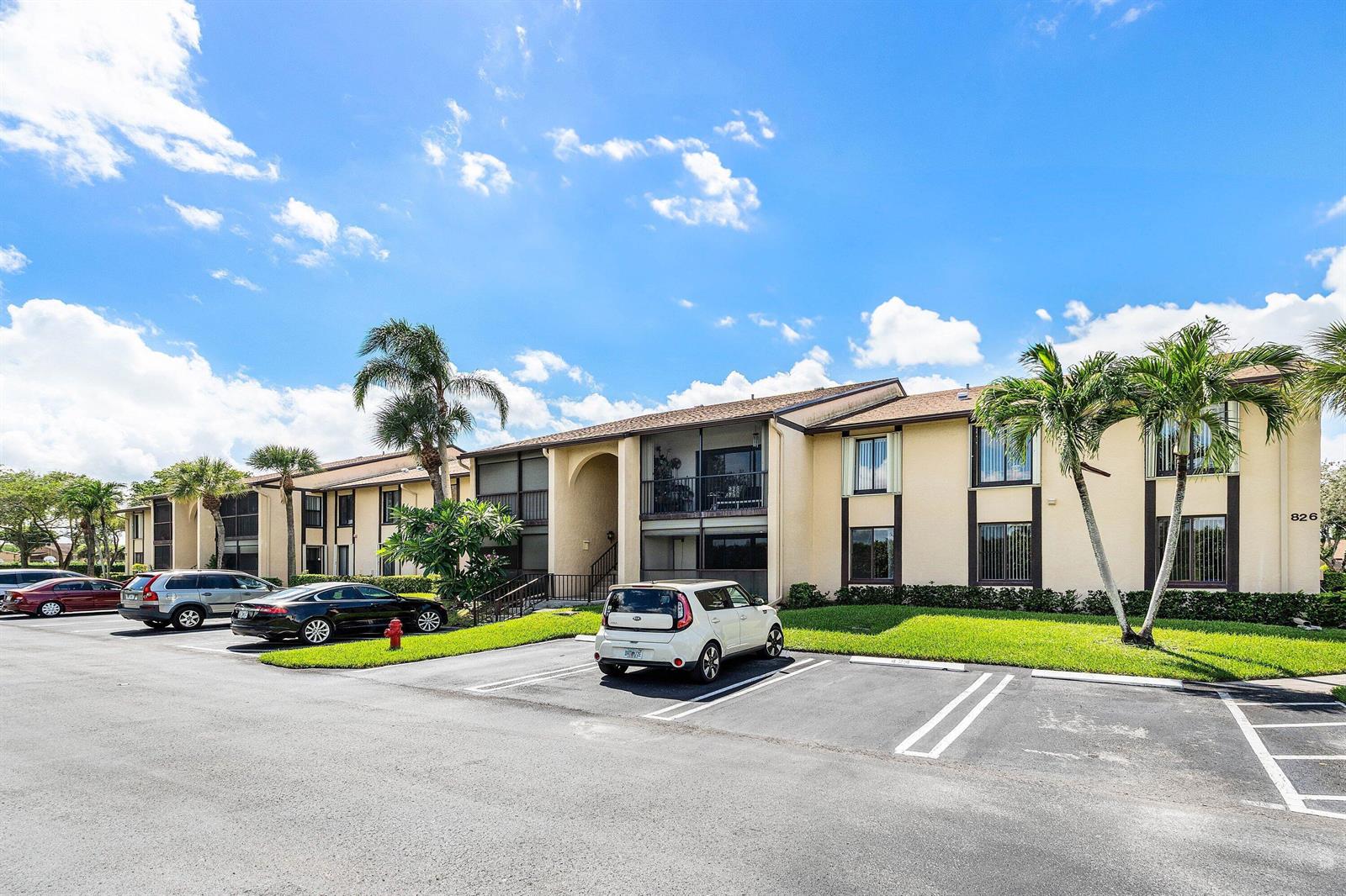 A two-story apartment building with a parking lot and palm trees under a blue sky — 826 Sky Pine Way # D1, FL 33415, FL