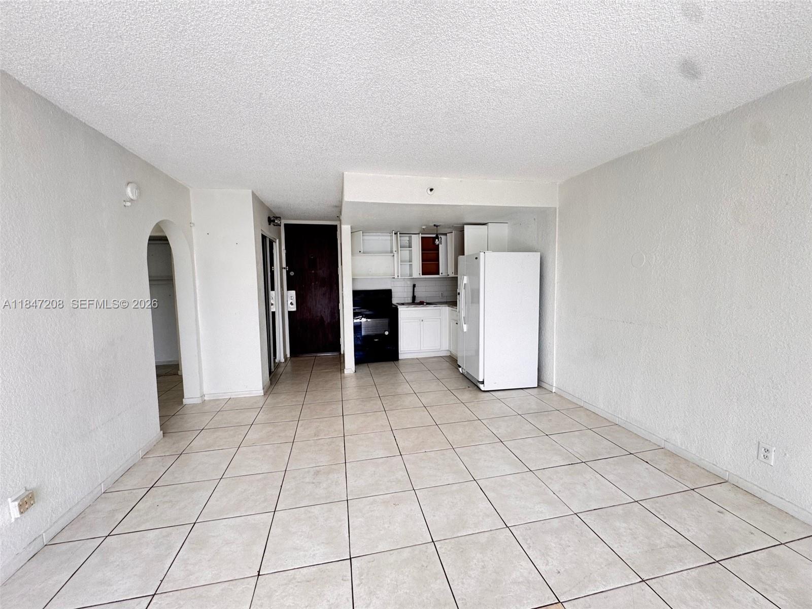 An open-concept living area features white walls, tiled floors, and a small kitchen corner — 16450 NW 2nd Ave # 207, Miami FL 33169, MIAMI, FL
