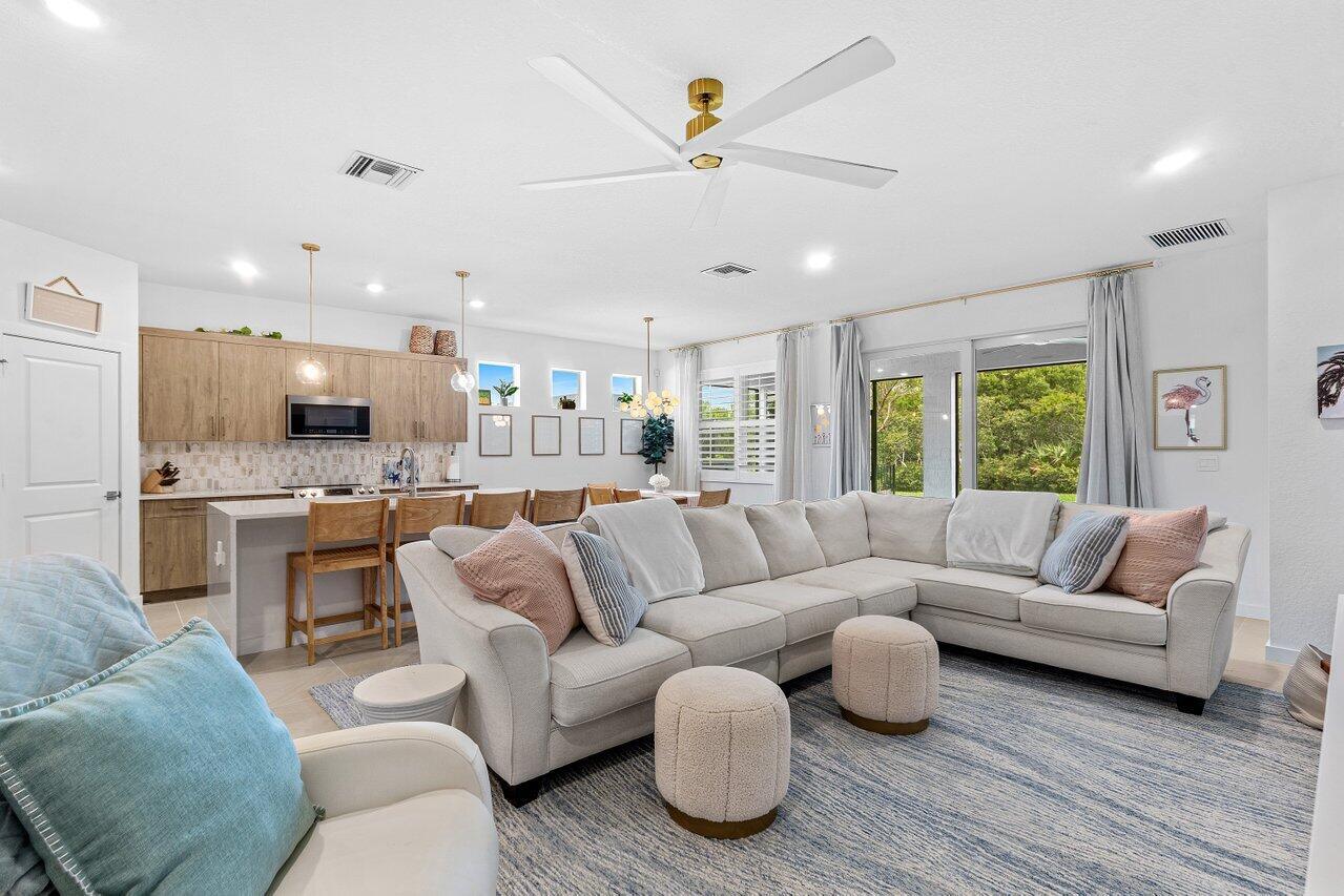An open-concept living room and kitchen featuring a large sectional sofa and light wood cabinetry — 1991 NE Ocean Dunes Drive, Jensen Beach FL 34957, JENSEN BEACH, FL