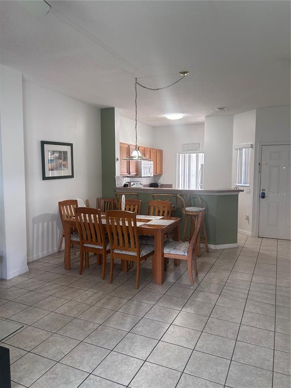 A dining area with a wooden table and chairs sits adjacent to a kitchen counter — 1064 PARK RIDGE CIRCLE, KISSIMMEE, FL