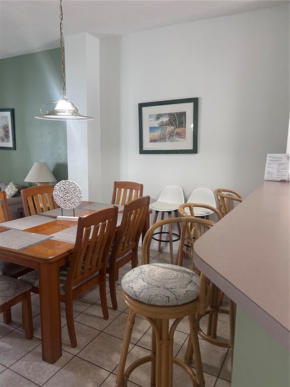 A dining area features a wooden table with chairs and a breakfast bar with stools — 1064 PARK RIDGE CIRCLE, KISSIMMEE, FL