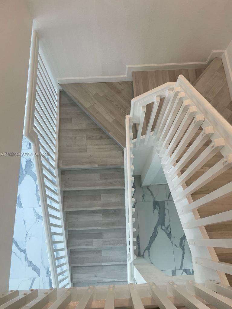 A high-angle view of a staircase with light wood-look steps and white railings — 10557 W 32nd Ln, Hialeah FL 33018, HIALEAH, FL