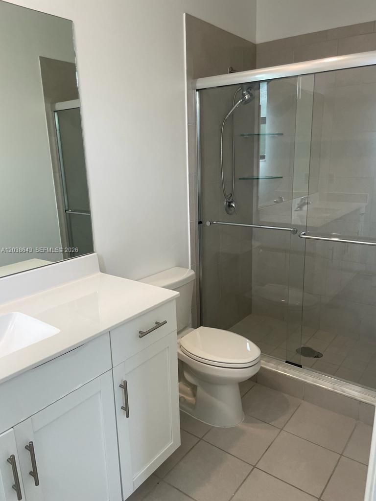 A bathroom features a white vanity, a toilet, and a glass-enclosed walk-in shower — 10557 W 32nd Ln, Hialeah FL 33018, HIALEAH, FL