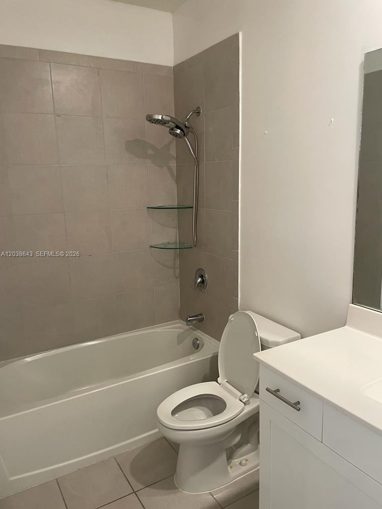 A bathroom features a white toilet, a vanity, and a tub with a tiled surround — 10557 W 32nd Ln, Hialeah FL 33018, HIALEAH, FL