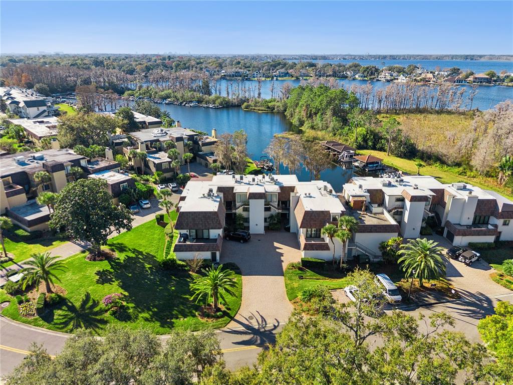 An aerial view shows multi-story residential buildings situated along a lake with boat docks — 6204 MASTERS BOULEVARD UNIT 202, ORLANDO, FL