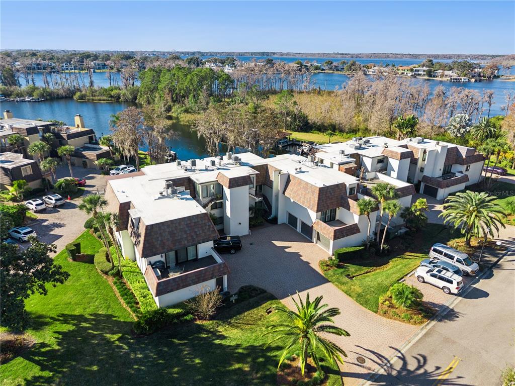 An aerial view shows a multi-unit residential building with a paved courtyard near a lake — 6204 MASTERS BOULEVARD UNIT 202, ORLANDO, FL