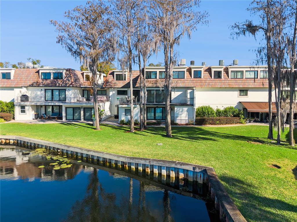 A multi-story residential building with balconies overlooks a canal and a grassy lawn — 6204 MASTERS BOULEVARD UNIT 202, ORLANDO, FL