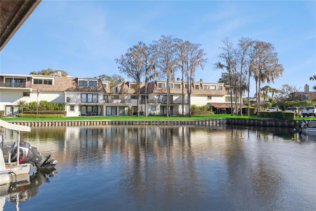A multi-story residential building sits along a canal with a boat docked in the foreground — 6204 MASTERS BOULEVARD UNIT 202, ORLANDO, FL
