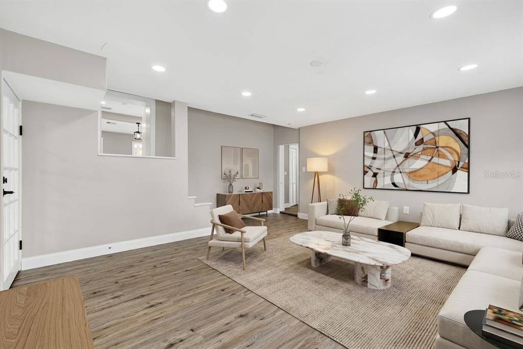 A living room features light gray walls, wood-look flooring, a sectional sofa, and recessed lighting — 3620 E TAMPA CIRCLE, TAMPA, FL