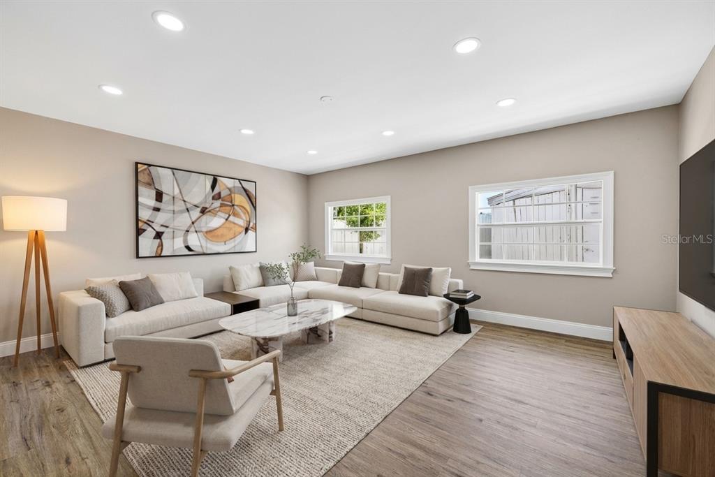 A living room features a sectional sofa, a marble coffee table, and light wood flooring — 3620 E TAMPA CIRCLE, TAMPA, FL